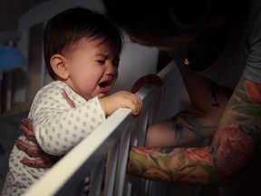 Parent trying to comfort crying baby in cribb