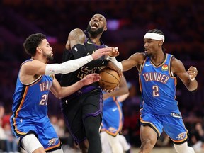 LeBron James #23 of the Los Angeles Lakers drives with the ball against Shai Gilgeous-Alexander