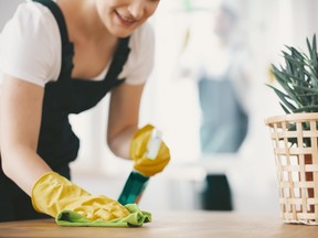Close-up on smiling housewife with yellow gloves cleaning table with cloth