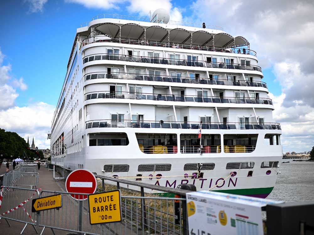 Passengers stand aboard the Bahamas-registered cruise ship Ambition after they were confined following the outbreak of a gastrointestinal illness onboard, at the Bordeaux port in Bordeaux, southwestern France on May 13, 2026.