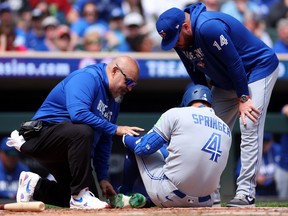 Blue Jays batter George Springer is checked by a medical trainer and manager John Schneider after getting hit by a pitch on the foot against the Twins during the third inning at Target Field in Minneapolis, Saturday, May 2, 2026.