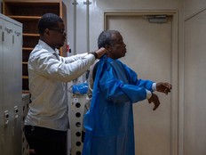 A worker (left) helps professor Jean-Jacques Muyembe, director general of the National Institute for Biomedical Research (INRB), to put on protective equipment before entering a laboratory in Kinshasa, Democratic Republic of the Congo, on May 20, 2026.