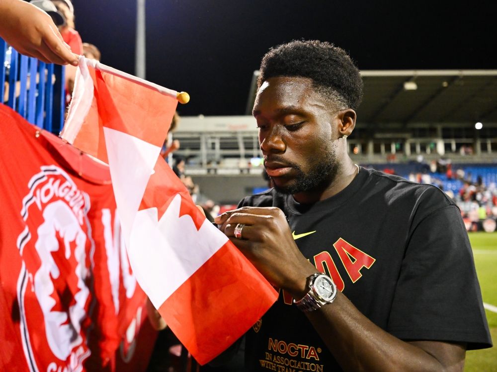 Alphonso Davies signs a Canadian flag at the conclusion of the international friendly match against the Republic of Ireland last week.