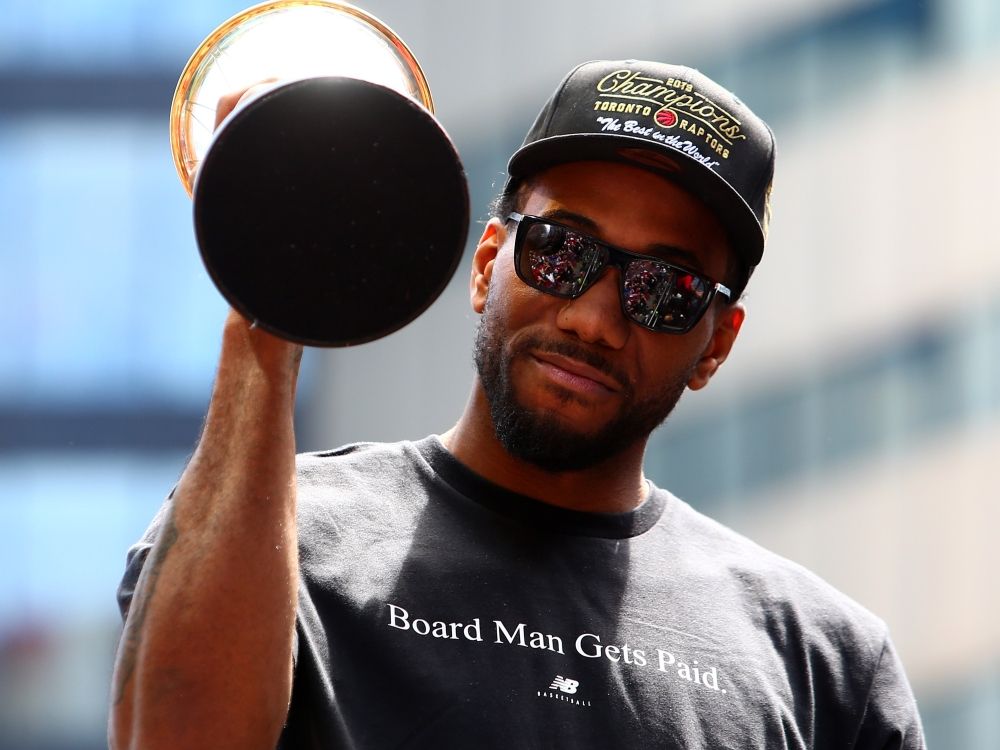 Kawhi Leonard holds the NBA Finals MVP trophy during the Toronto Raptors victory parade in 2019.