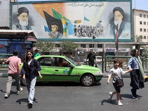 Iranians walk past a mural depicting late Iranian supreme leaders Ayatollah Ali Khamenei (left) and Ayatollah Ruhollah Khomeini (right) in Tehran on June 18, 2026.