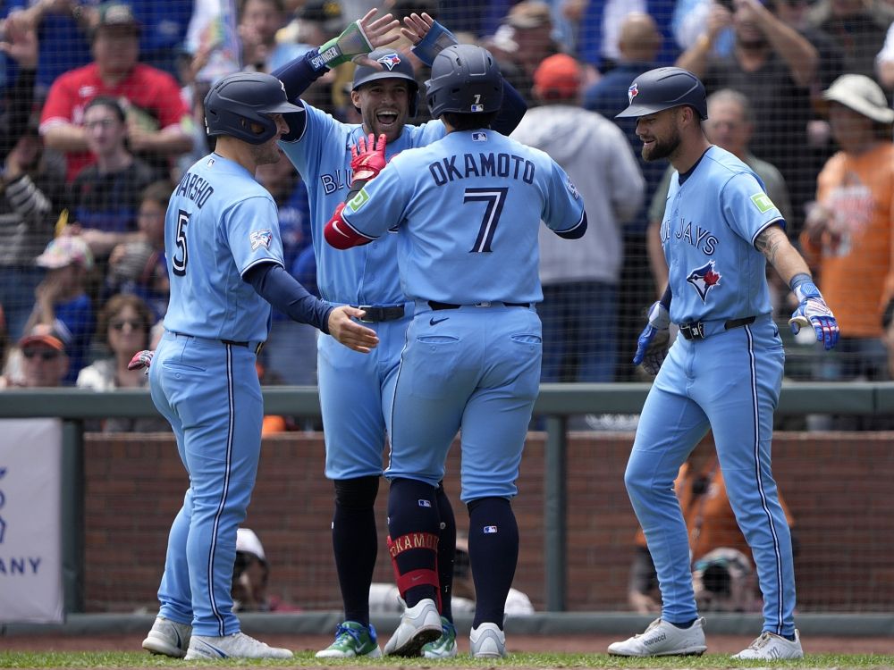Kazuma Okamoto of the Toronto Blue Jays is congratulated by teammates after hitting a grand slam home run against the San Francisco Giants.