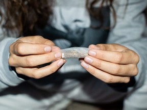 A young woman prepares a marijuana joint.
