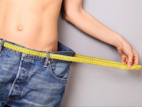 A woman demonstrates that she has lost weight.