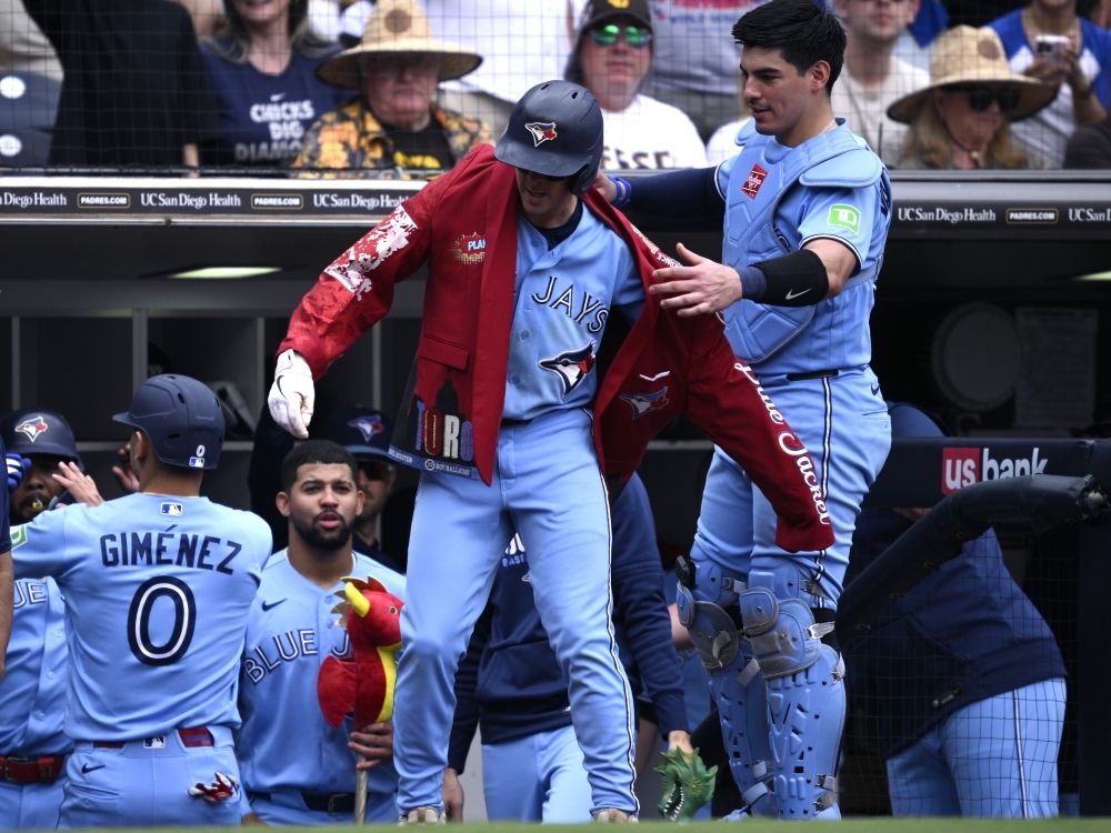 Ernie Clement of the Toronto Blue Jays has the home run jacket placed on him by Brandon Valenzuela after hitting a two-run home run against the San Diego Padres.