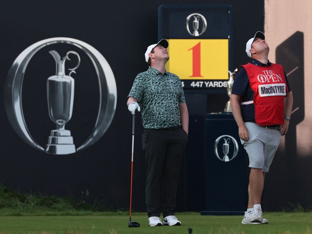 Scotland's Robert MacIntyre and his caddie Mike Burrows look at a drone flying above the 1st tee on day one of the 154th Open Golf championship at Royal Birkdale.