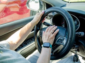 An older woman, driving a car, presses the horn