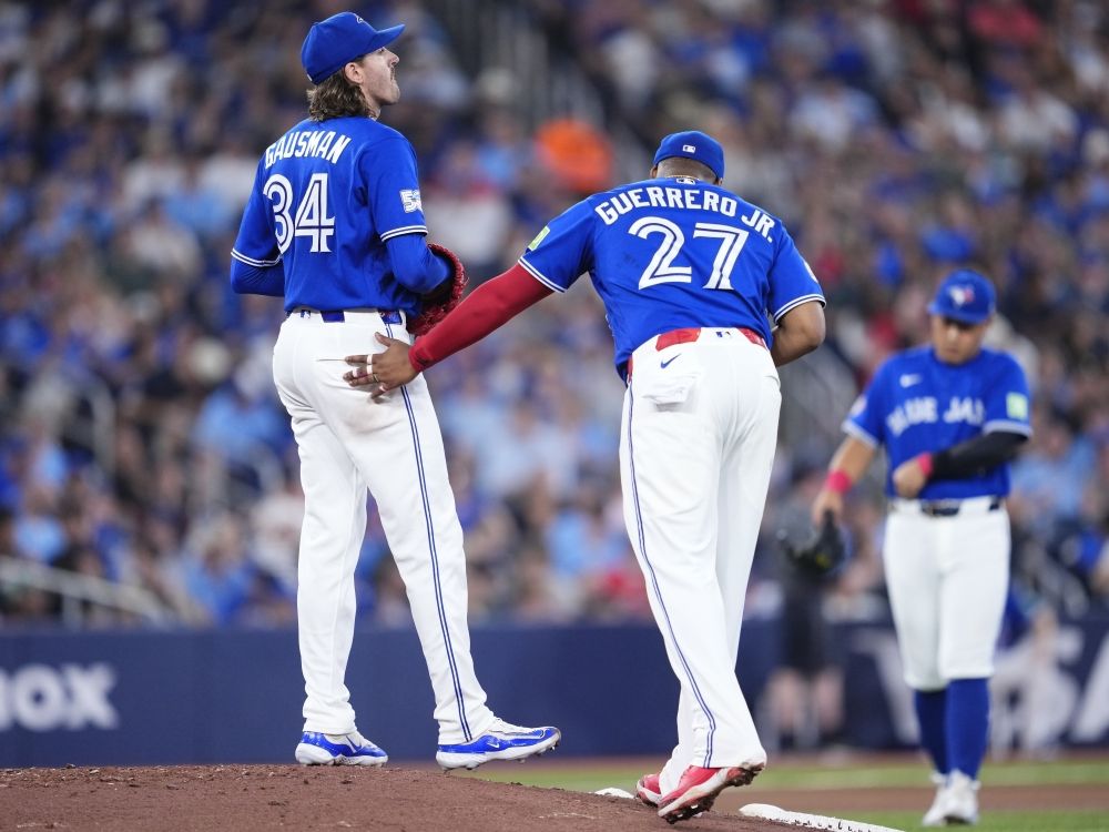 Kevin Gausman of the Toronto Blue Jays reacts just before being pulled from the game as Vladimir Guerrero Jr. approaches during a break in play against the Tampa Bay Rays.