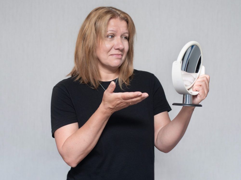 A middle-aged woman studies her reflection