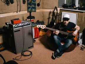 A man plays a guitar in his basement.