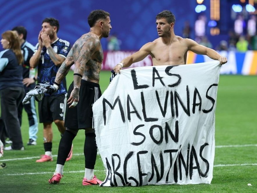 Argentina players hold up a banner saying 'The Malvinas (Falkland Islands) are Argentine'.