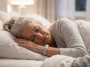 Senior woman sleeping in bed wearing a fitness tracker. Elderly female resting soundly while monitoring sleep quality with wearable smart band. Health tracking concept