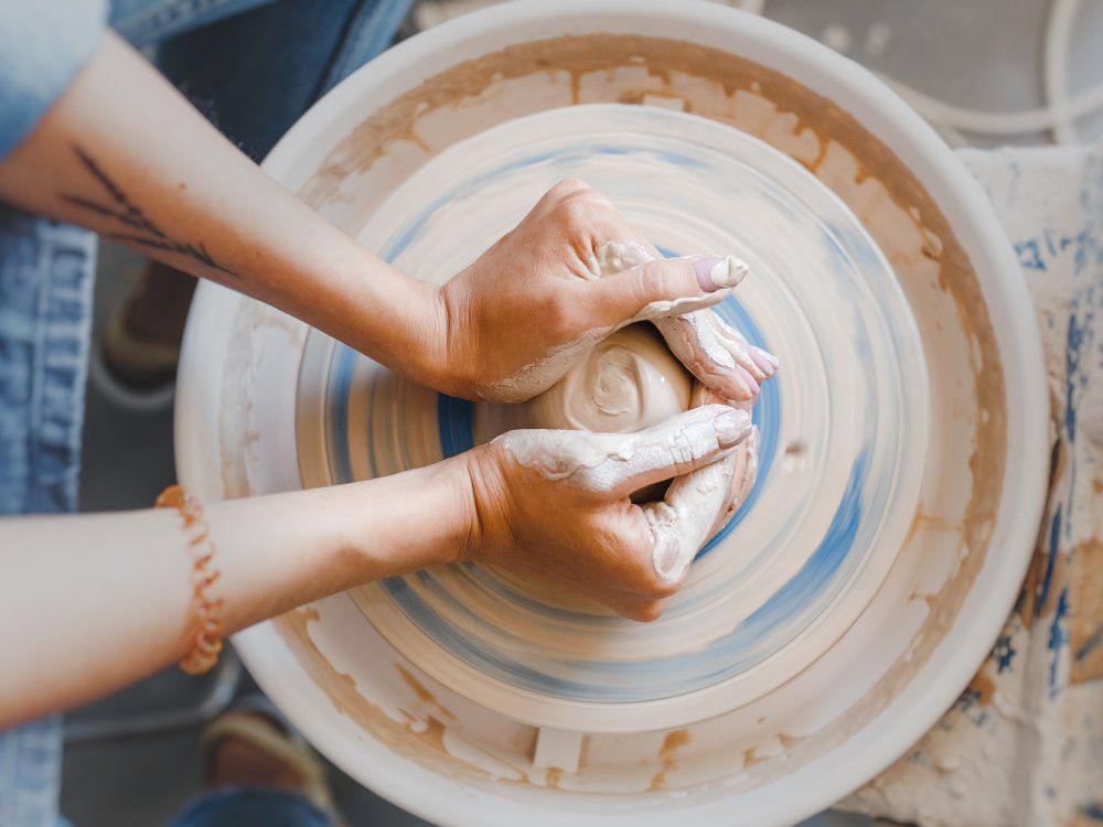 Top view of hands with clay making of a ceramic pot on the pottery wheel, hobby and leisure with pleasure concept