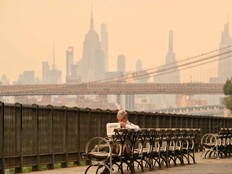 A person on a bench reads a newspaper as wildfire smoke from Canada causes hazy conditions on July 16, 2026 in New York.