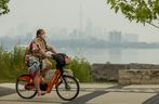 רוכב אופניים רעול פנים רוכב לאורך פארק Humber Bay Shores כשהאוויר העשן מסתיר חלקית את קו הרקיע של טורונטו ביום רביעי, 15 ביולי 2026.