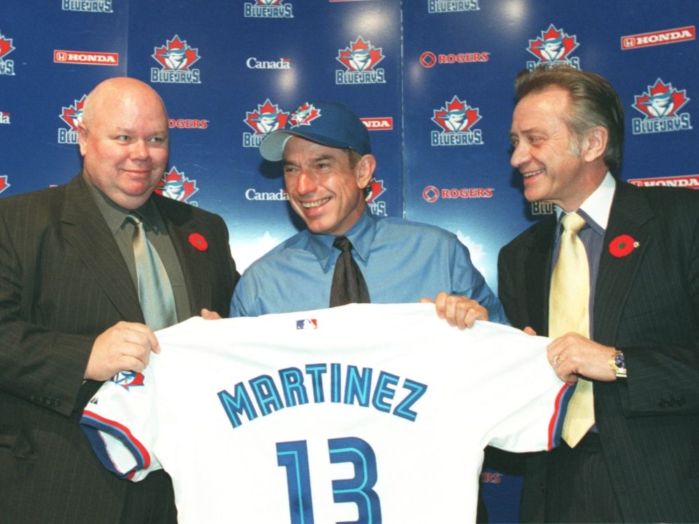 Buck Martinez is flanked by Gord Ash and Paul Godfrey as he holds up his jersey after becoming manager of the Toronto Blue Jays.