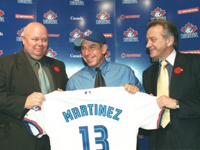 Buck Martinez is flanked by Gord Ash and Paul Godfrey as he holds up his jersey after becoming manager of the Toronto Blue Jays.