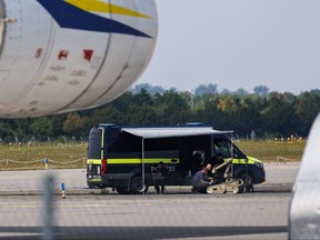 Police investigators work on a tarmac with a robot capable of defusing explosives.
