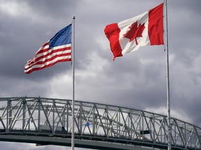 The U.S. and Canada flags flutter next to the Blue Water Bridge border crossing in Point Edward, Ont.