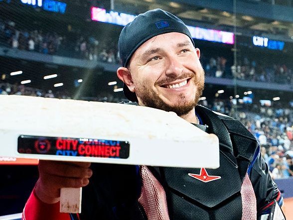Alejandro Kirk #30 of the Toronto Blue Jays smiles while holding the base to celebrate his first major league stolen base following his team's win over the Texas Rangers in their MLB game at the Rogers Centre on August 15, 2025 in Toronto, Ontario, Canada.