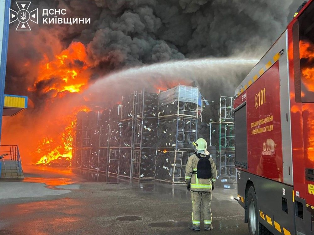 In this handout photograph taken and released by the Ukrainian Emergency Service on Saturday, Aug. 29, 2026, a Ukrainian rescuer stands next to a firetruck as they work to extinguish a fire in a warehouse following an air attack at an undisclosed location in the Kyiv region, amid the Russian invasion of Ukraine.