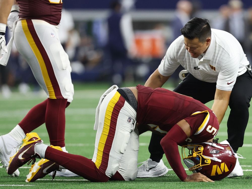 A member of the Washington Commanders medical staff attends to quarterback Jayden Daniels after he sustained an injury against the Dallas Cowboys.