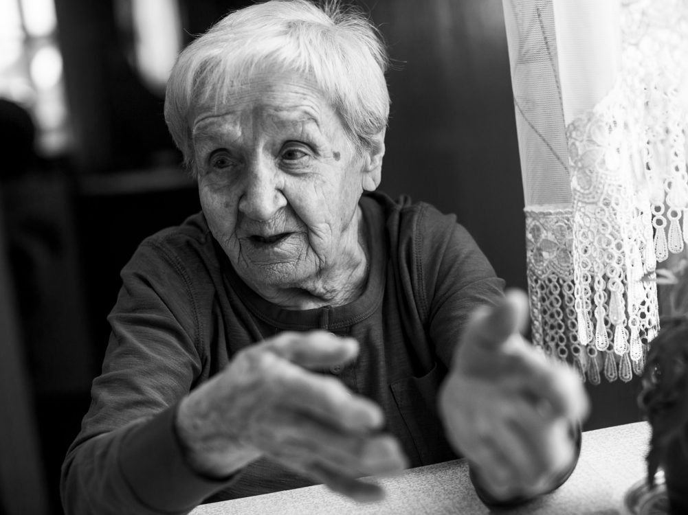 An old woman takes part in a one-sided conversation.
