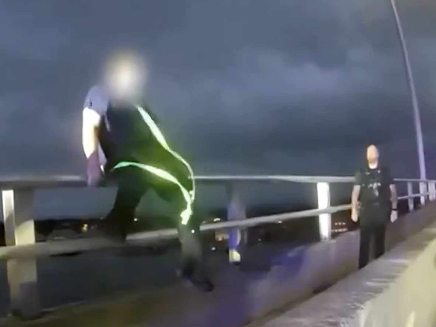 A man experiencing a mental health crisis is seen stepping off a bridge’s railing in Florida.