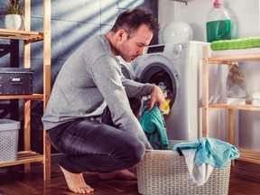 A man puts clothes into a washing machine