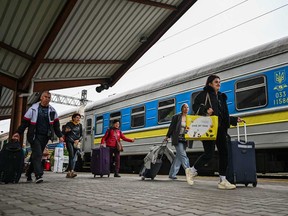 In this file photo taken on Sept. 30, 2022, Ukrainians carry their bags as they get off a train from Zaporizhzhia at Przemysl train station in Przemysl, Poland.