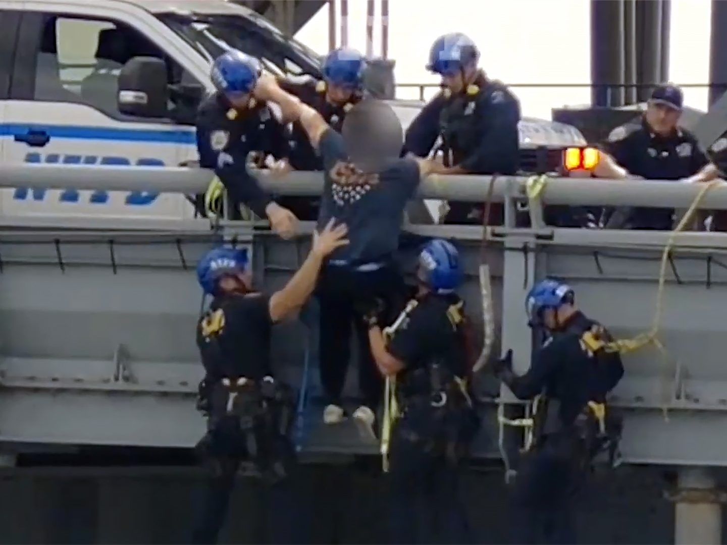 New York City Police officers are seen pulling a man up from the ledge of the Williamsburg Bridge in Brooklyn.