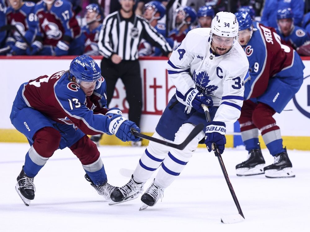 T.J. Hughes of the Colorado Avalanche and Auston Matthews of the Toronto Maple Leafs compete for the puck.