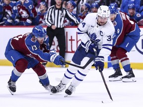T.J. Hughes of the Colorado Avalanche and Auston Matthews of the Toronto Maple Leafs compete for the puck.