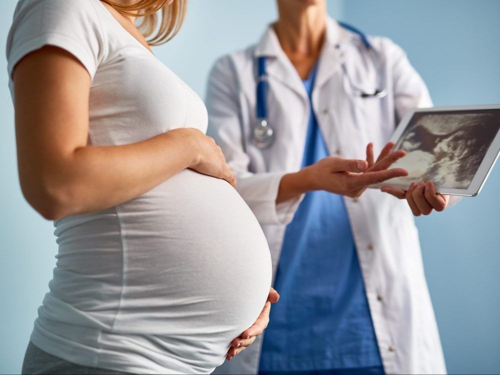 A doctor explains ultrasound scan results to a pregnant woman.