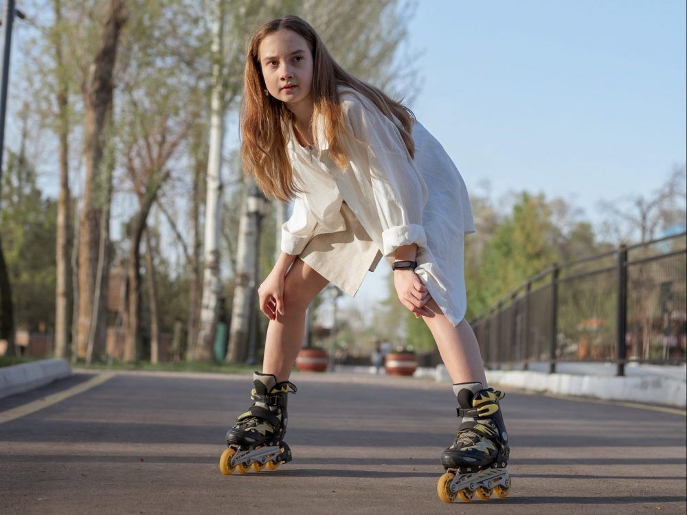A teenage girl rollerblades on a bright sunny day.