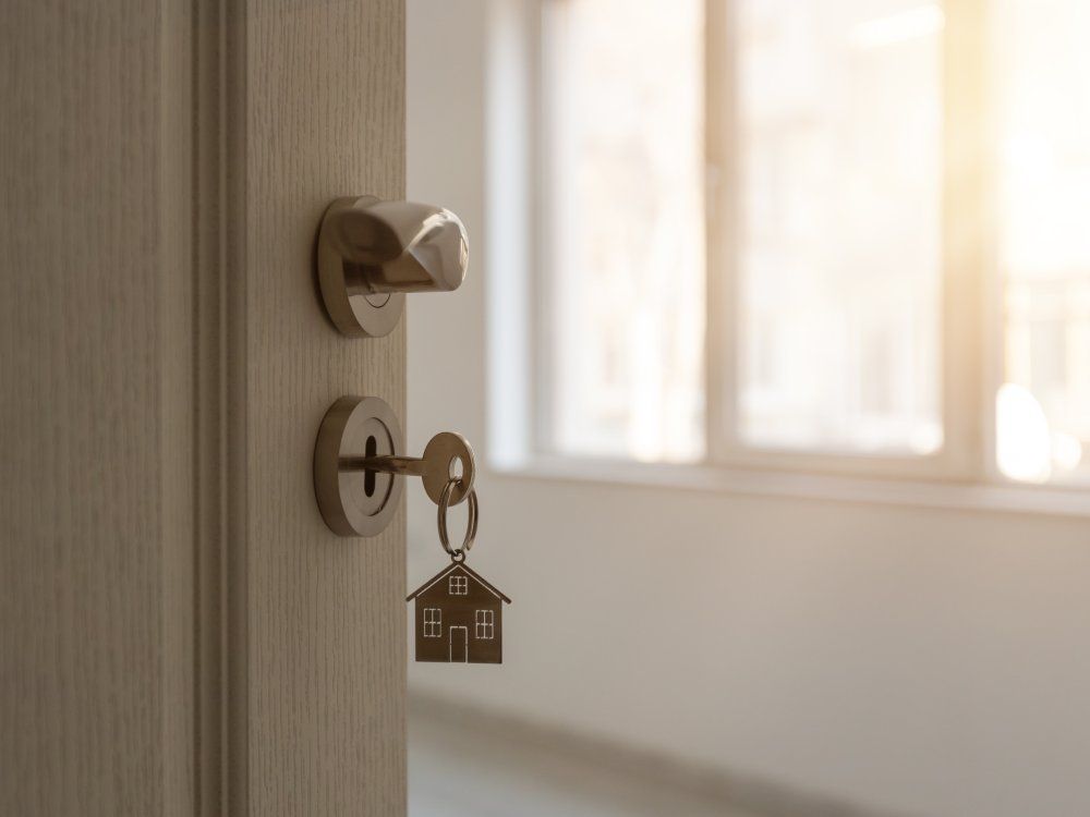 Open door to a new home with key and home shaped keychain. Mortgage, investment, real estate, property and new home concept