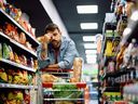 Mid adult man having a headache while buying groceries in supermarket.