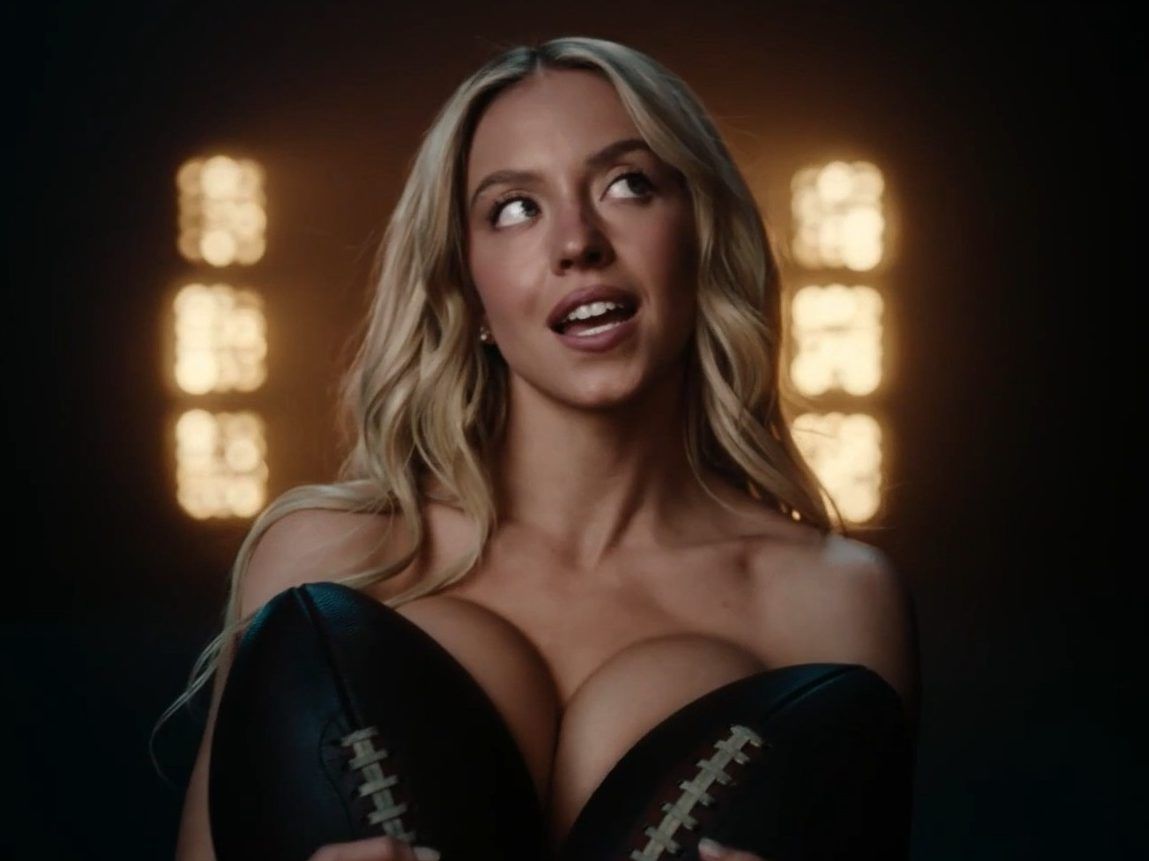 Sydney Sweeney holding two footballs to her chest in second Novig ad.