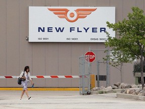 A worker walks past a New Flyer Industries' sign at the plant's Winnipeg headquarters. The company is now slated to manufacture a fully electric bus for commercial purposes.