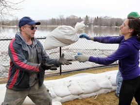Volunteer Kayla Dosch (right) tosses a sandbag to Mitch Pelland in May 2011. (BRIAN DONOGH/Winnipeg Sun files)
