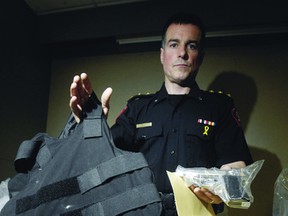 A Calgary police officer displays a bulletproof vest used by criminals in that city. In Winnipeg, a growing number of gang members and other criminals are sporting body armour, police sources say. (LYLE ASPINALL/QMI Agency Files)