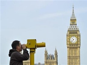 A man looks through a telescope opposite Big Ben and the Houses of Parliament, in central London May 6, 2011. (Reuters/Toby Melville)