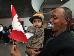 Yonas Tesfazion shows his niece, five-month-old Nestalem-Kilbrom, the Canadian flag during swearing in ceremonies.  Yonas is from North Africa and has been in Canada for five years. PERRY MAH/EDMONTON SUN    QMI AGENCY
