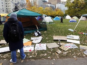 A pedestrian looks at numerous Occupy Ottawa support signs in Confederation Park on Nov. 1 (Chris Roussakis/QMI Agency file photo)