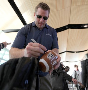 Winnipeg Blue Bombers DT Doug Brown signs a souvenir football for seven-year-old fan Justis Hellegards as players prepared to leave Winnipeg Richardson International Airport to play in the CFL Grey Cup in Vancouver. (JASON HALSTEAD, Winnipeg Sun)