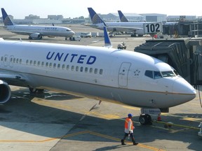 A ground crew member walks past a United Airlines airplane as it sits at a gate at Newark Liberty International Airport in Newark, New Jersey, June 18, 2011.  REUTERS/Gary Hershorn